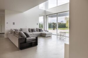 Soggiorno moderno con pavimenti in resina grigio chiaro effetto cemento, alternativa elegante ai pavimenti microcemento. Soluzione ideale per ambienti contemporanei, con indicazioni sul costo pavimento in resina per ristrutturazioni di interni.