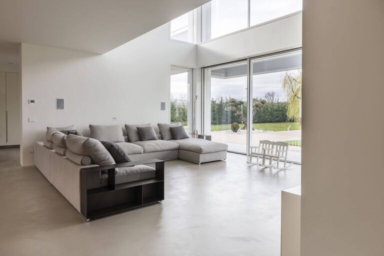 Soggiorno moderno con pavimenti in resina grigio chiaro effetto cemento, alternativa elegante ai pavimenti microcemento. Soluzione ideale per ambienti contemporanei, con indicazioni sul costo pavimento in resina per ristrutturazioni di interni.