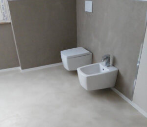 Bagno moderno con pavimento in resina effetto cemento grigio chiaro, soggiorno luminoso con resina continua senza fughe, design contemporaneo minimalista